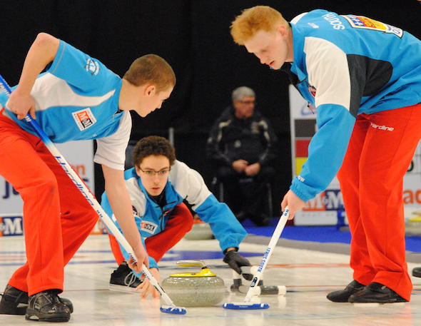 Quebec skip Félix Asselin delivers rock, with sweepers Émile Asselin, left, and Lewis South keeping things clean. (Photo, Amanda Rumboldt)