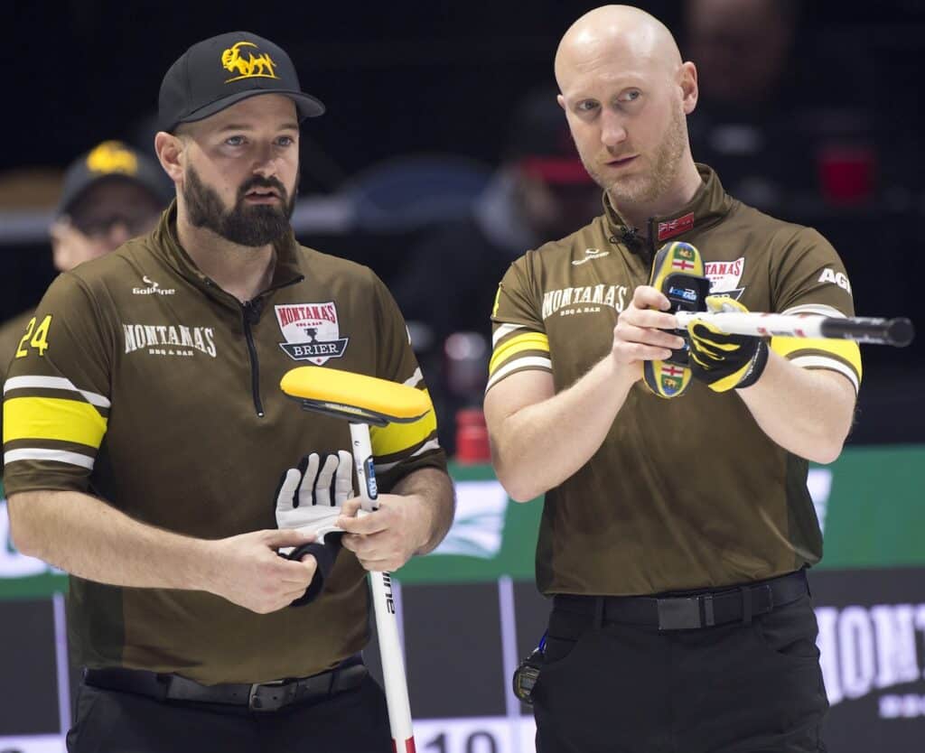 Reid Carruthers, left, and Brad Jacobs plot strategy during action Thursday night at the Brandt Centre. (Photo, Curling Canada/Michael Burns)