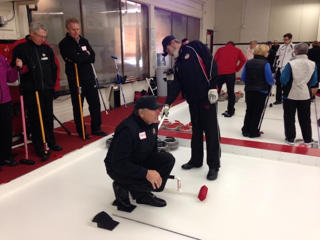 Earle Morris plays the part of a novice curler while instructor Michel St. Marseille adjusts his position in the hack during the Train the Trainer session (Photo courtesy Ottawa Curling Club)