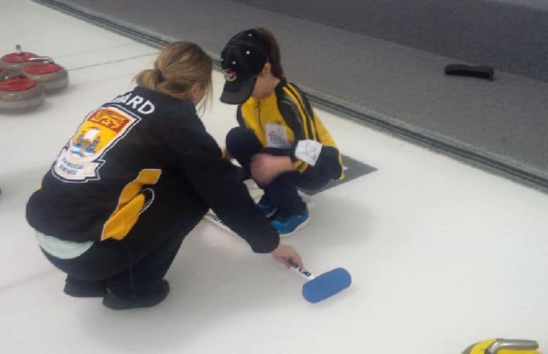 Curler and Rocks & Rings instructor Cathlia Ward offers a curling lesson to a young curler during a break at the 2015 Canadian Mixed Curling Championship in North Bay, Ont. (Photo courtesy Cathlia Ward)