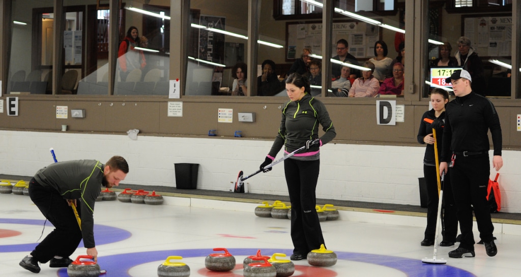 Charley Thomas sweeps a rock into the rings, watched by teammate Kalynn Park and opponents Bowie Abbis-Mills and Tess Bobbie during the final of the 2015 Mixed Doubles Curling Trials at the Ottawa Hunt & Golf Club (Claudette Bockstael photo)