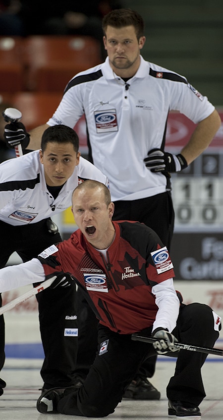 Équipe Canada capitaine Pat Simmons appelle des instructions pour que les balayeuses Enrico Pfister de la Suisse, à gauche, et Reto Keller regardent. (Photo, Curling Canada / Michael Burns)