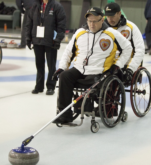 Manitoba skip Dennis Thiessen, left, prepares to deliver stone with backing from teammate Mark Wherrett at the 2014 Canadian Wheelchair Curling Championship.