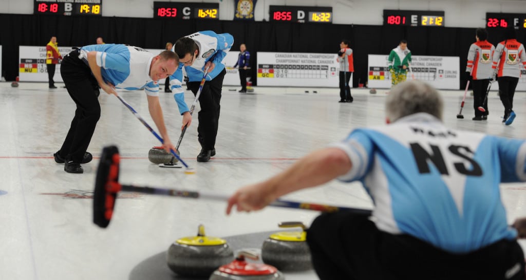 Nova Scotia sweepers Ian Wilson and Brad Wilson are hard at work while third Logan Ward calls the line during Tuesday night action at the 2015 Travelers Curling Club Championship in Ottawa (Curling Canada/Claudette Bockstael Photo)