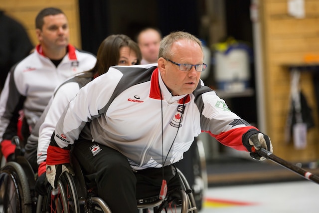 Team Canada second Dennis Thiessen delivers his rock assisted by third Ina Forrest and lead Mark Ideson at the World Wheelchair Curling Championships, Lucerne, Switzerland (WCF/Céline Stucki photo)