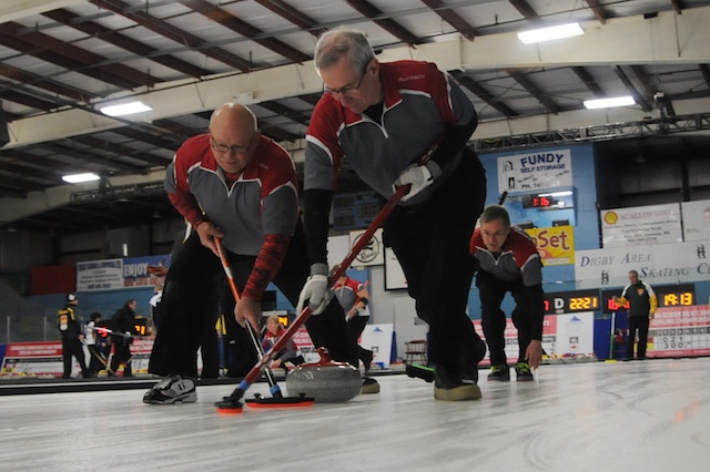 Northwest Territories third Brian Kelln and second Ben McDonald sweep lead Richard Klakowich's rock at the 2016 Canadian Seniors in Digby, N.S. (Curling Canada/Mike Lewis photo)