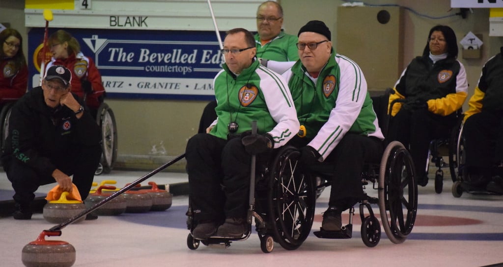 Saskatchewan skip Darwin Bender delivers his stone with help from teammate Lloyd Thiele at the 2016 Wheelchair Curling Championship in Regina (Curling Canada/Morgan Daw photo) 