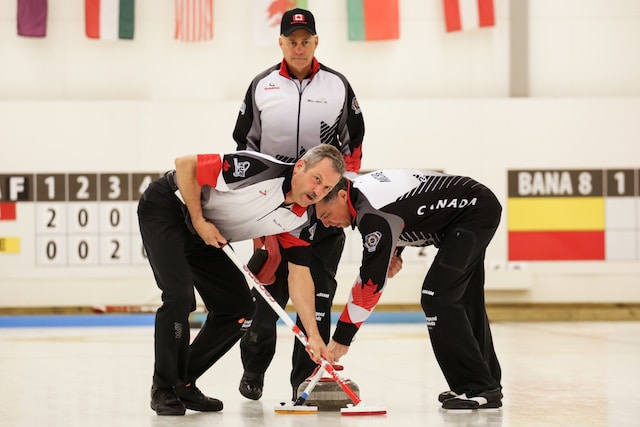 Dale Michie and Dean Moxham sweep skip Randy Neufeld’s rock at the 2016 World Senior Men’s Curling Champioships at the Karlstad Curling Arena (WCF/Céline Stucki photo)