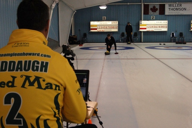 Wayne Middaugh runs the video equipment as curler Skid Crease tries to keep the laser’s red dot in the middle of his rock (Photo Jean Mills)