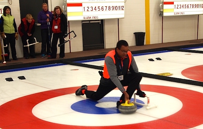 Dr. Neville Headley practices his delivery while his teammates and coach look on. (Photo by Lisa Shamchuk)